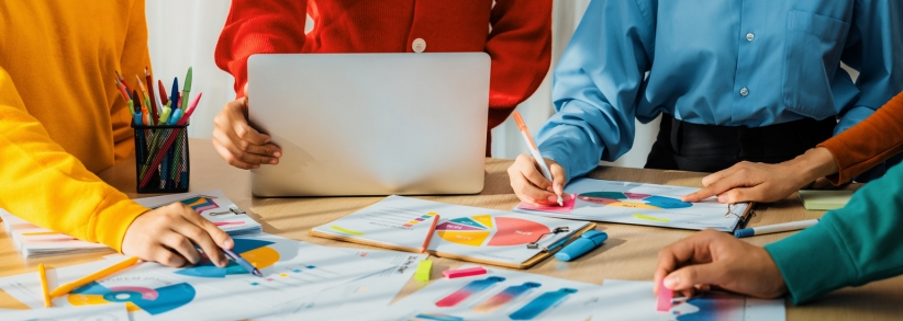 Marketing professionals hands working at a table on computer, graphs and writing